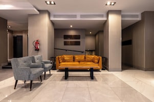 A lobby with a sofa, armchairs, and a fire extinguisher.