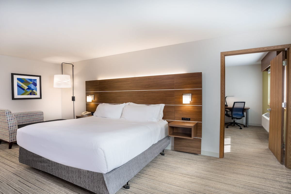 A modern hotel room with a large bed, bedside tables, a desk, and a chair.