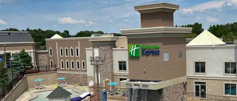 A Holiday Inn Express building with a pool area, outdoor seating, and a waterfall feature.