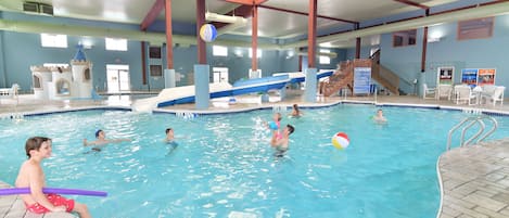 Une piscine intérieure dotée de plusieurs couloirs, d’un toboggan et d’un espace de jeux.