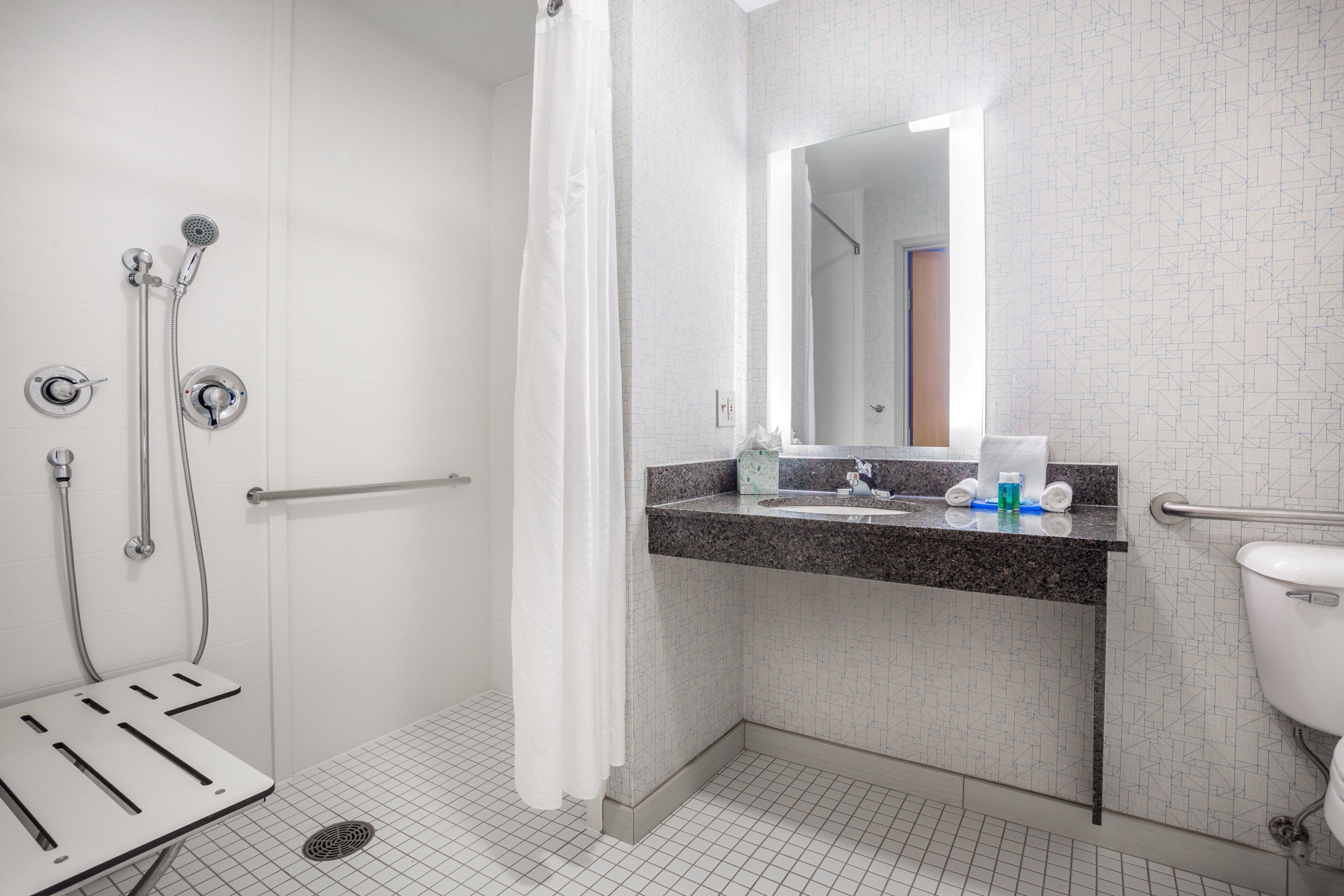 A modern bathroom with a shower, a sink with a mirror, and a toilet.