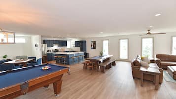 A spacious living area with a pool table, a dining table, and a sofa.