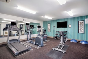 A gym with treadmills, elliptical machines, and weight equipment.