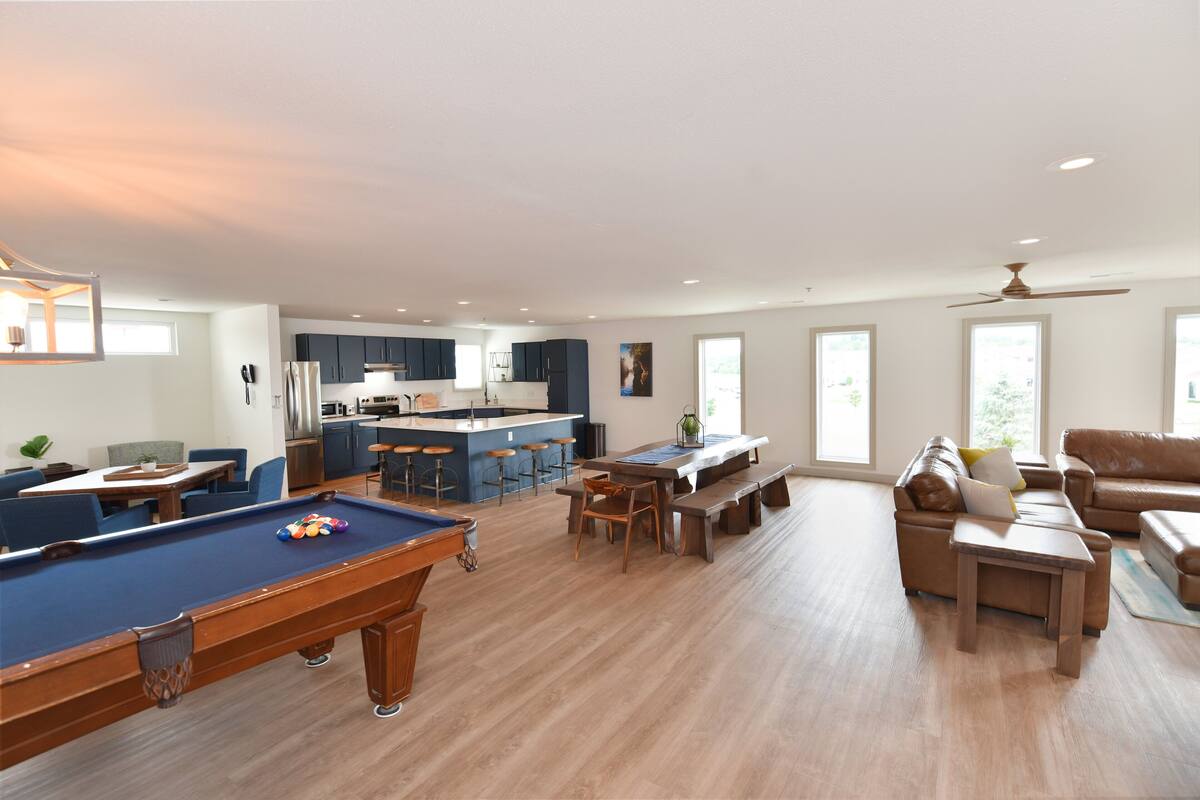 A spacious living area with a pool table, a dining table, and a sofa.