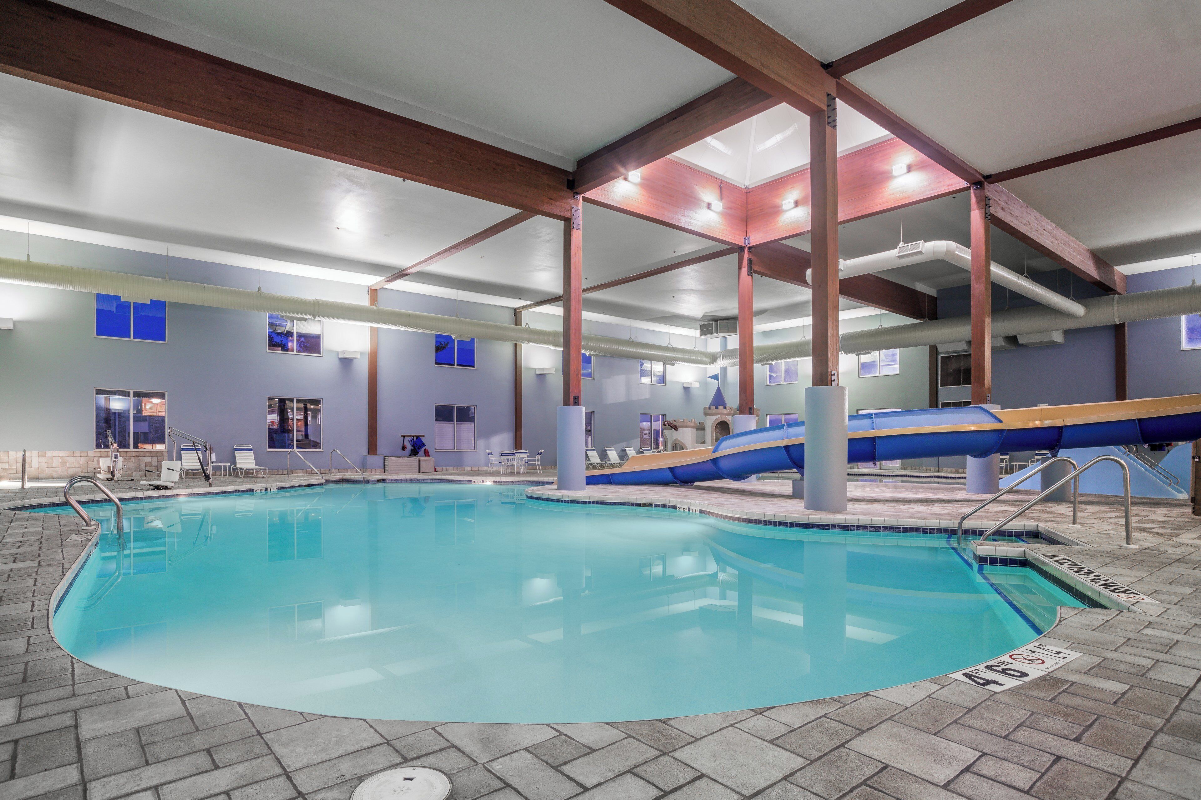 Une piscine intérieure à l’eau claire, entourée d’un sol carrelé et bordée de briques.