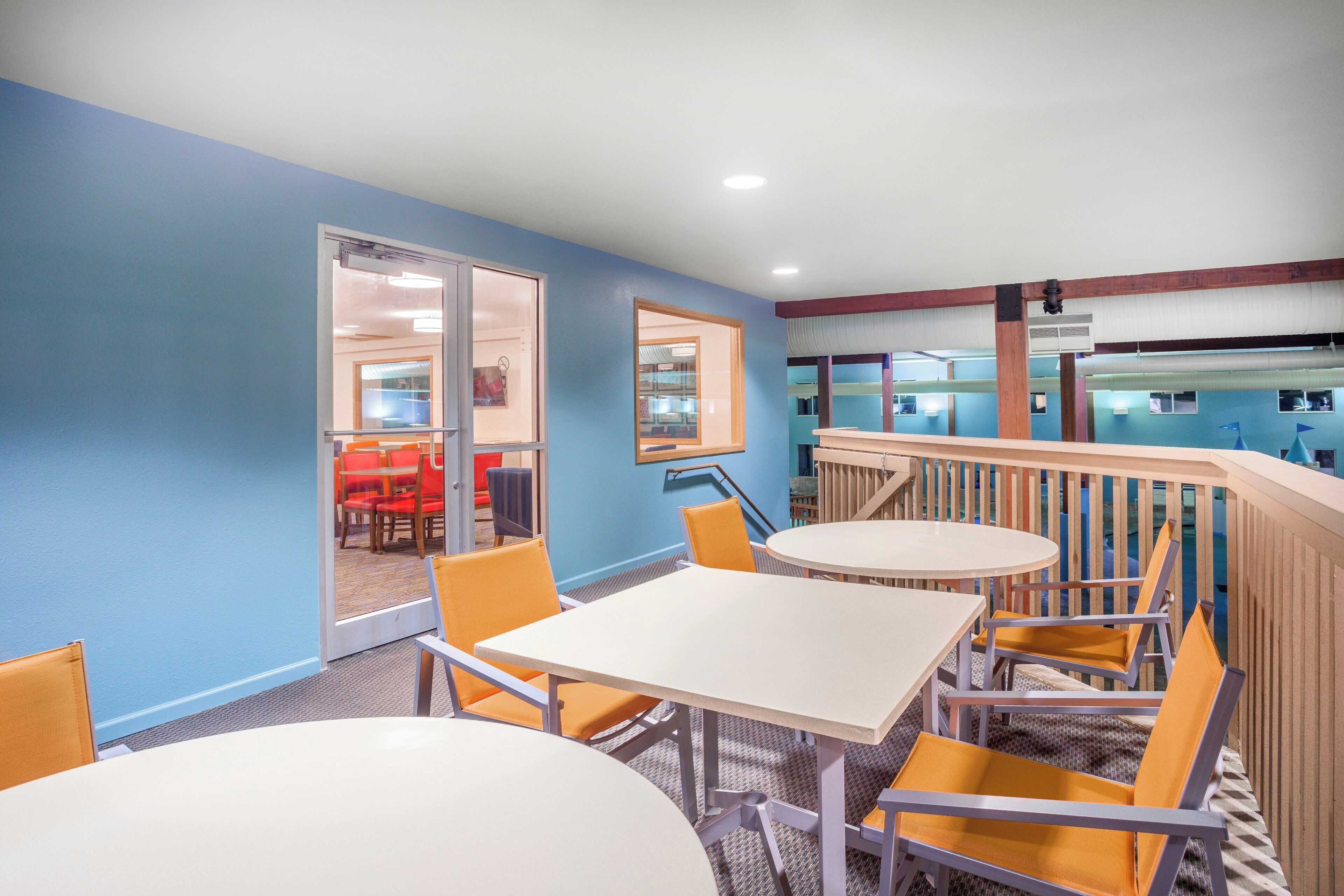 A hotel room with a blue wall, a white table, and orange chairs.