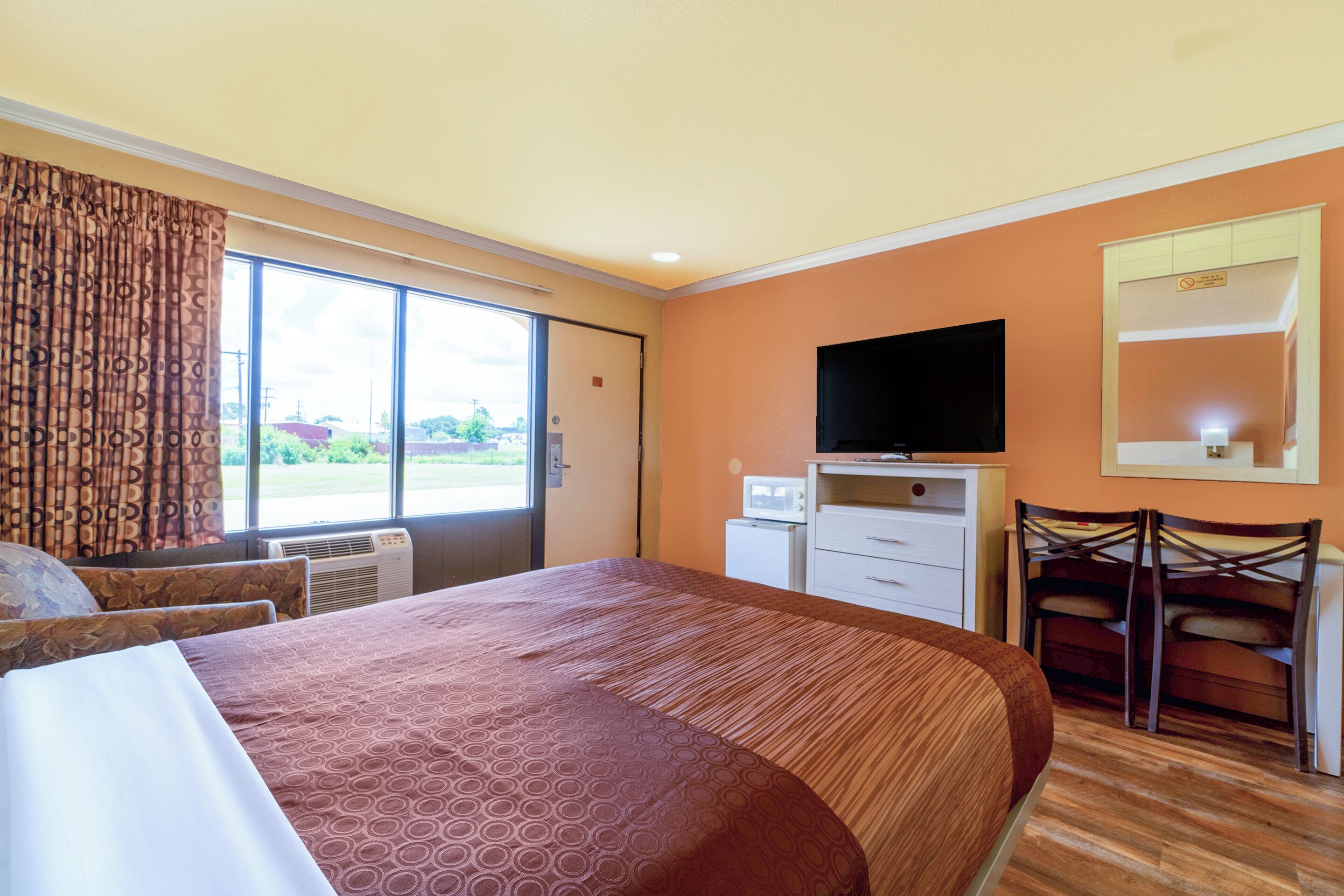 Una habitación de hotel con una cama grande, televisión, escritorio y silla.