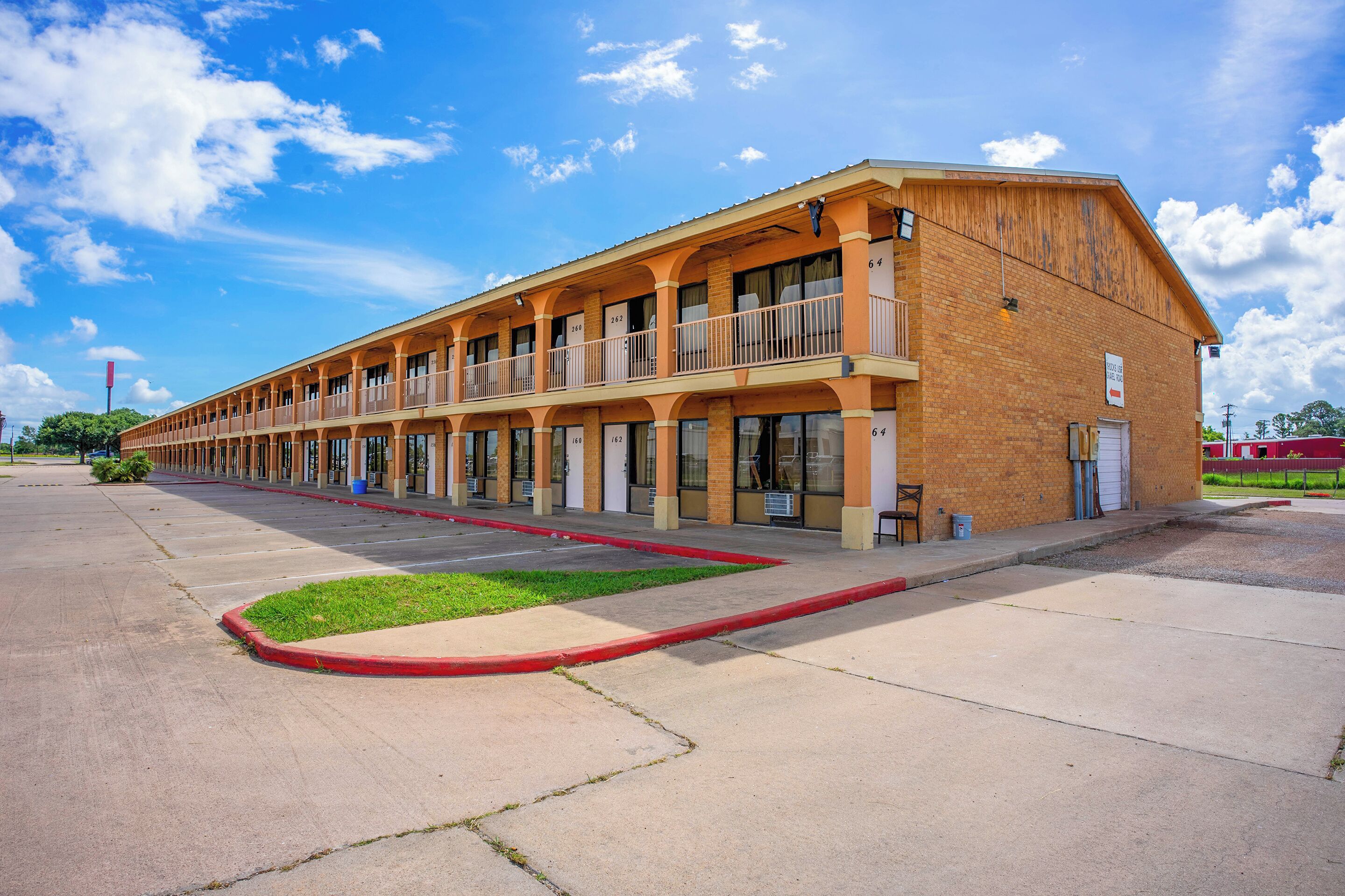 A two-story motel with a row of rooms on the ground floor and a single-story structure on the upper floor.