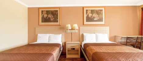 Ein Hotelzimmer mit zwei Einzelbetten, einem kleinen Tisch, zwei Stühlen, einem Nachttisch mit Lampen und zwei gerahmten Bildern an der Wand.