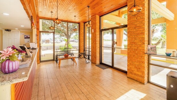 A reception area with wooden ceiling, large windows, a reception desk, and a seating area with a bench and chairs. - River Valley Motor Inn (La Grange)