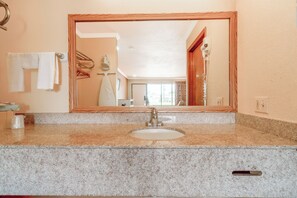 A bathroom with a granite countertop, a white sink, and a wooden-framed mirror.