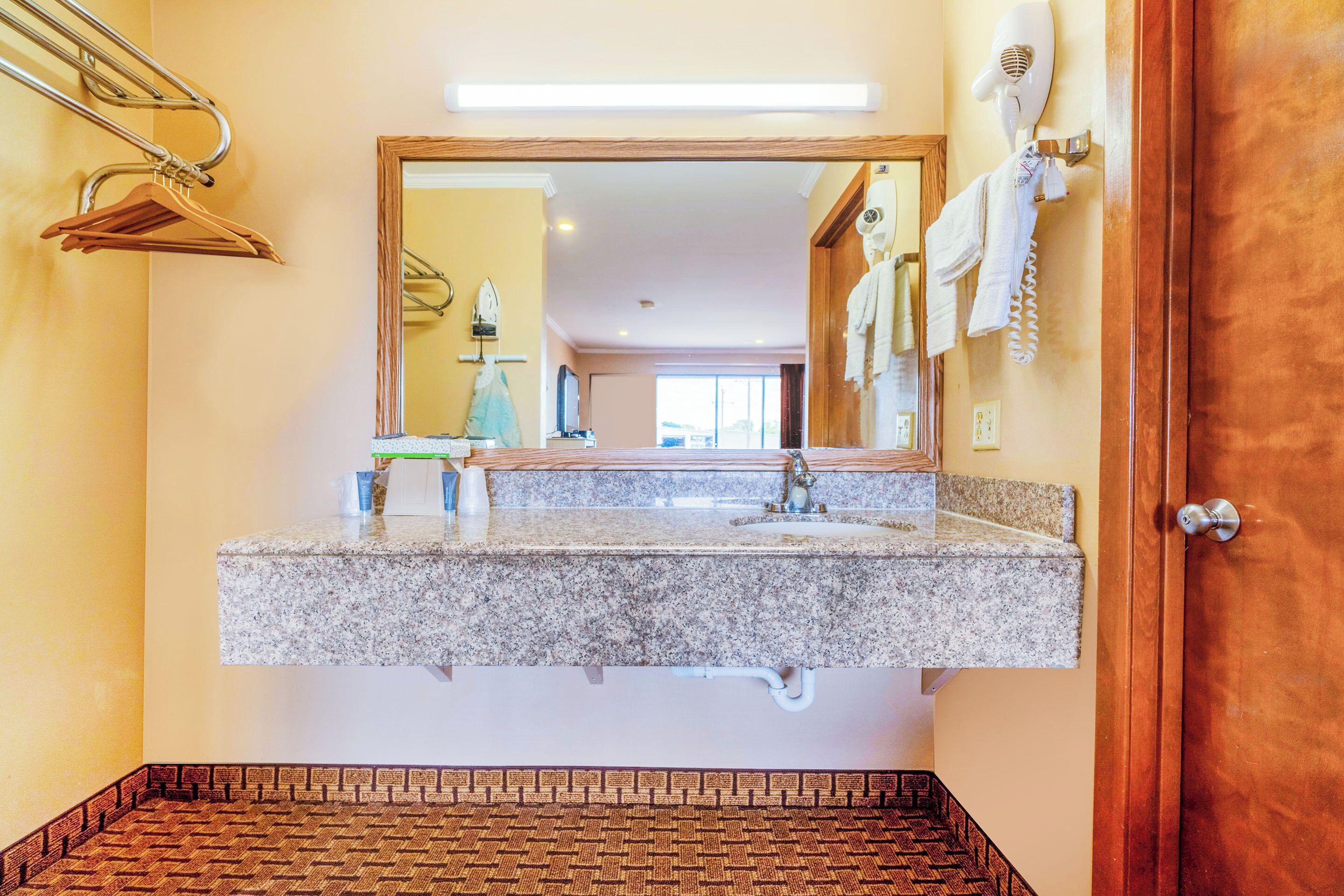 A bathroom with a granite countertop sink, a mirror, a towel rack, and a hairdryer.