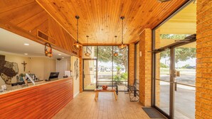 A reception area with a wooden ceiling, a reception desk, and a large window providing a view of the outside. - River Valley Motor Inn (La Grange)