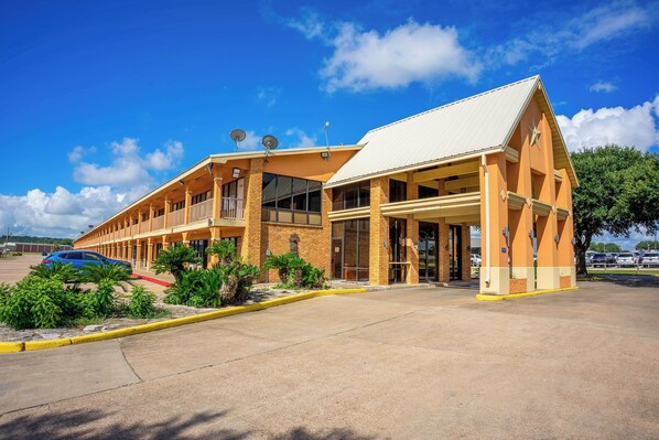 A hotel with a two-story structure, a covered entrance, and a parking lot.
