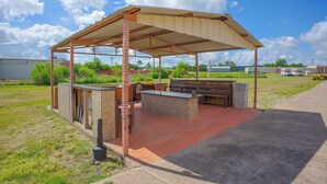 An outdoor patio with a covered barbecue area, stone counter, and seating. - River Valley Motor Inn (La Grange)