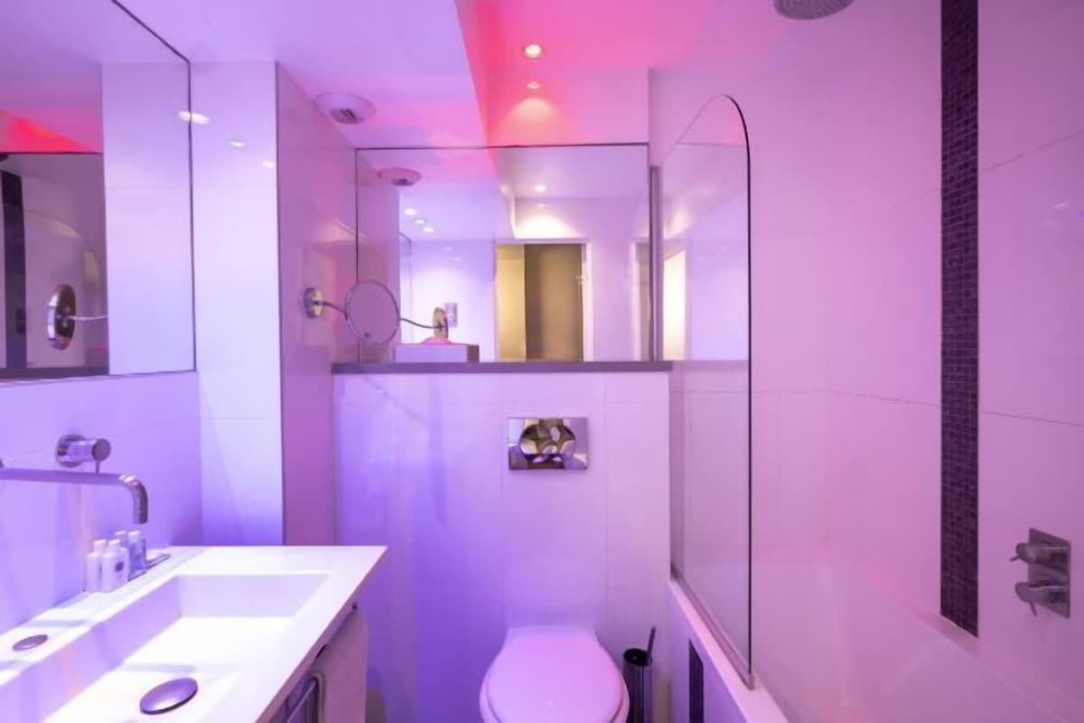 A modern bathroom with a glass shower enclosure, a white sink with a mirror, and a toilet.