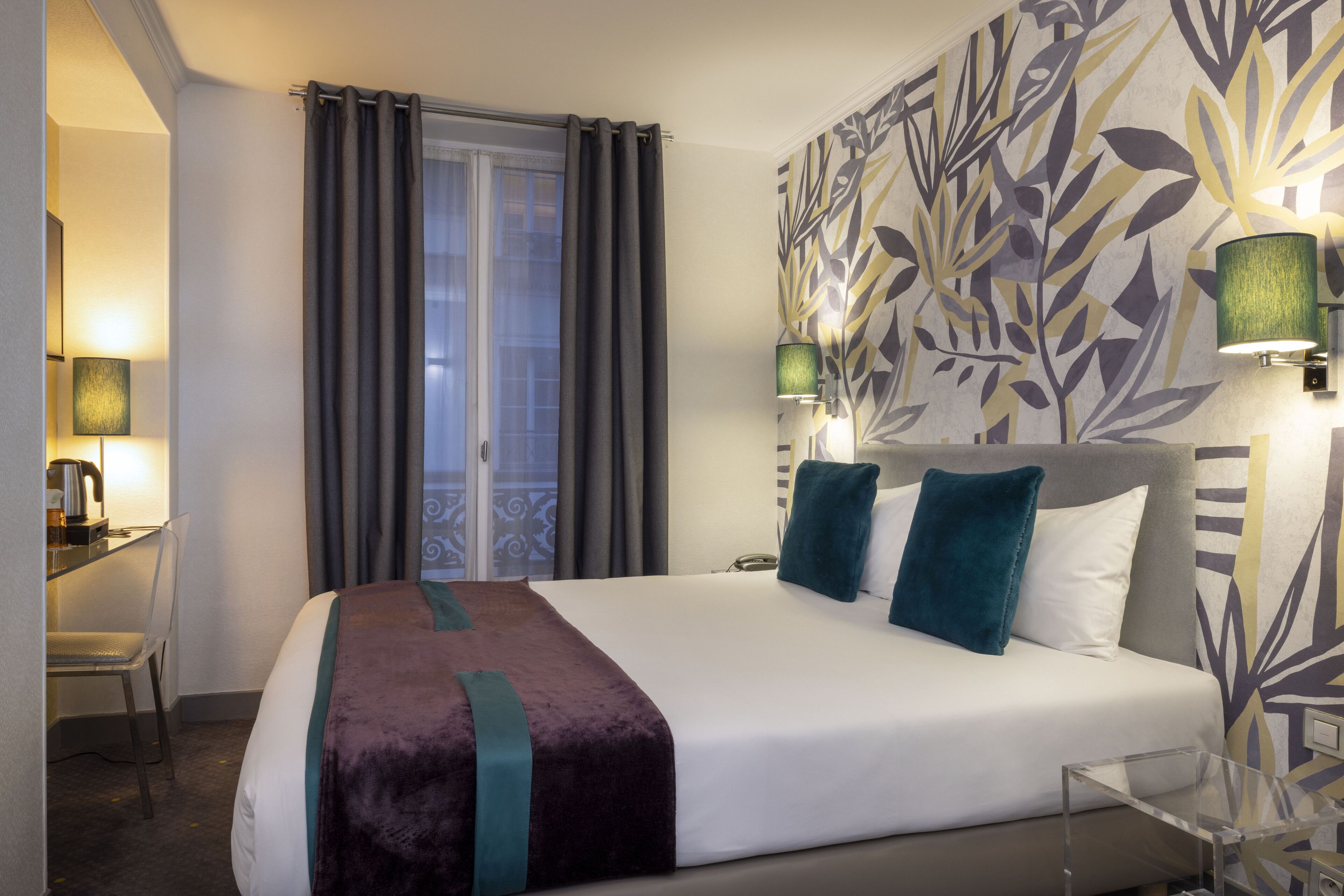 A hotel room with a bed, a desk, and a chair.