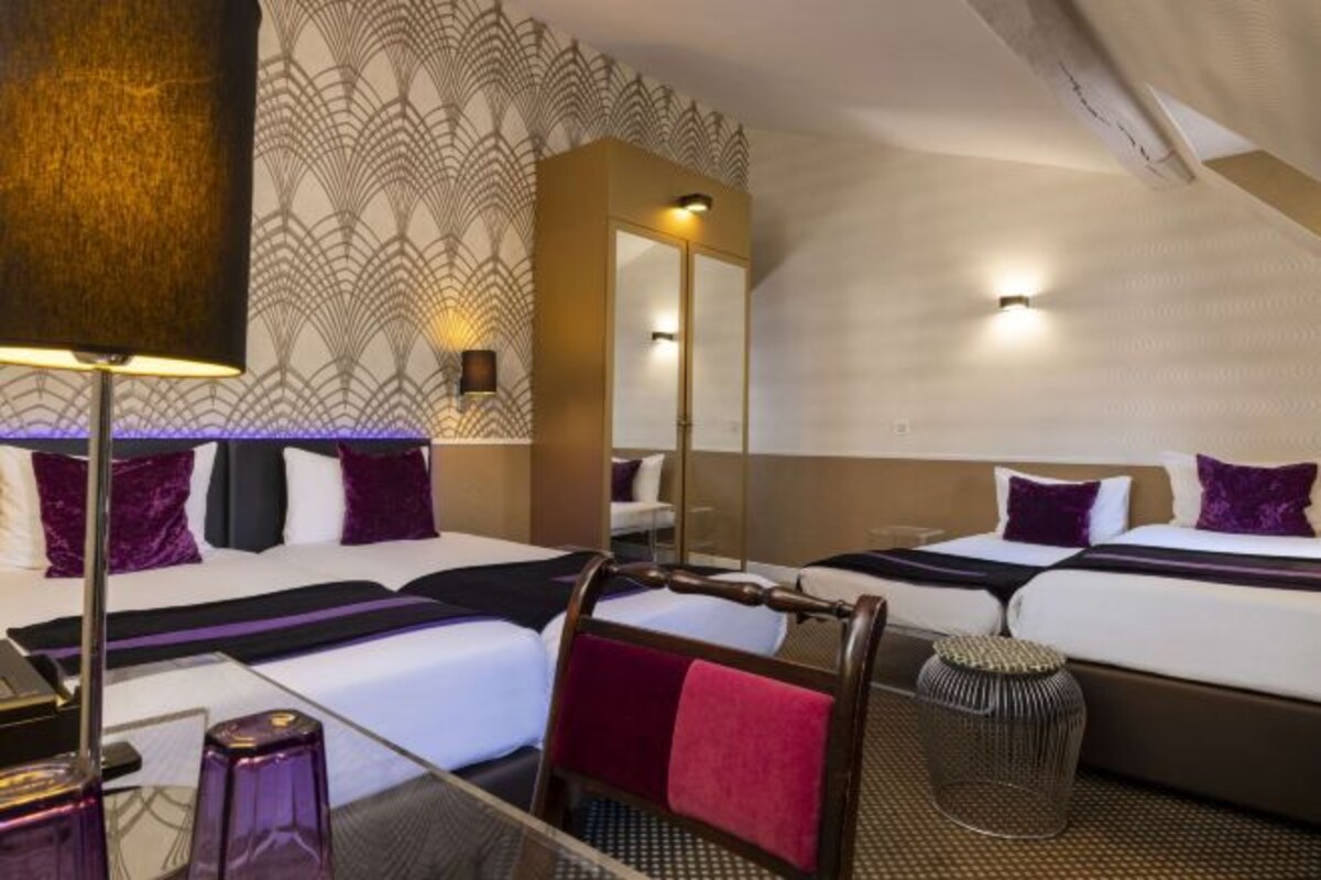 A hotel room with two beds, a large mirror, a desk, and a chair.