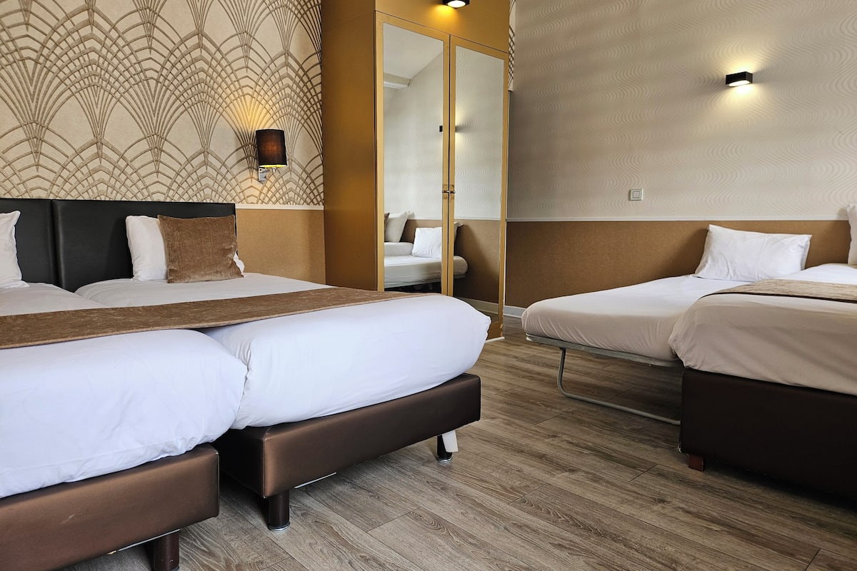 Een hotelkamer met twee bedden, een grote spiegel en een behang met patroon.