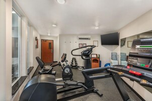 A gym with cardio machines, weights, and a television.