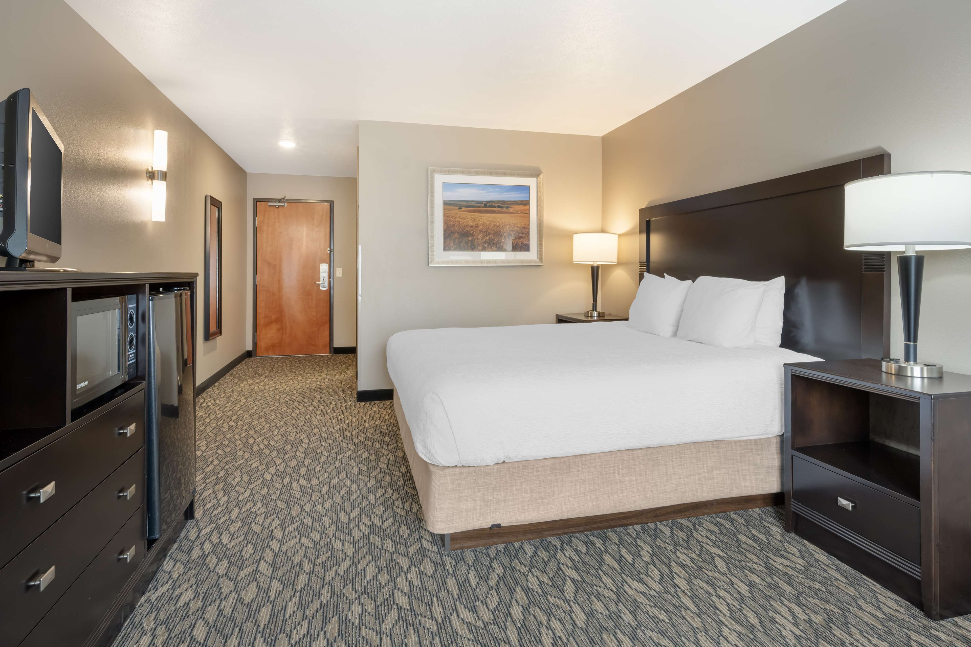 A hotel room with a bed, a TV, a desk, and a lamp.