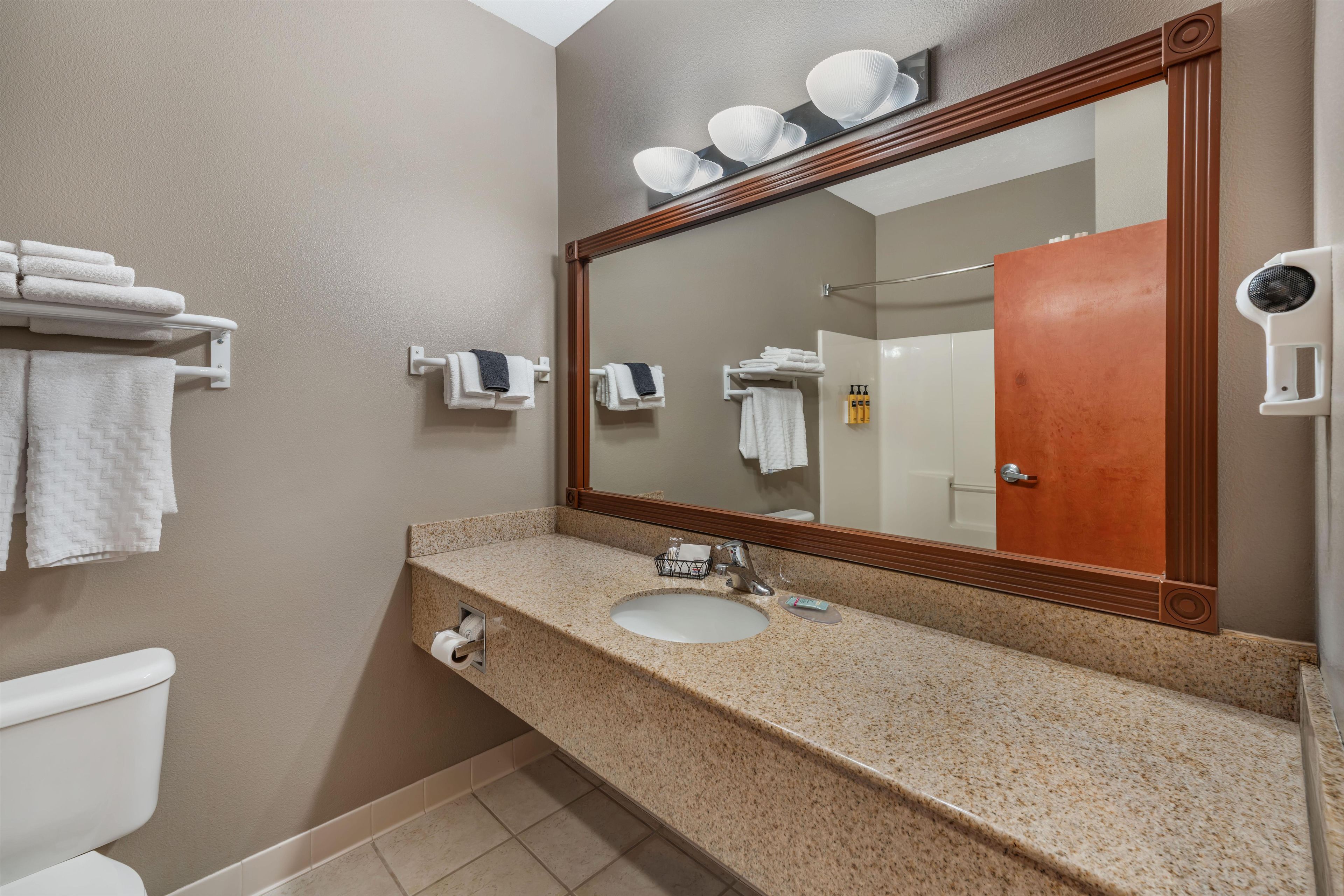 A bathroom with a sink, mirror, towel rack, and toilet.