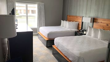 Una camera d'albergo con due letti, una scrivania, una sedia e vista all'esterno.