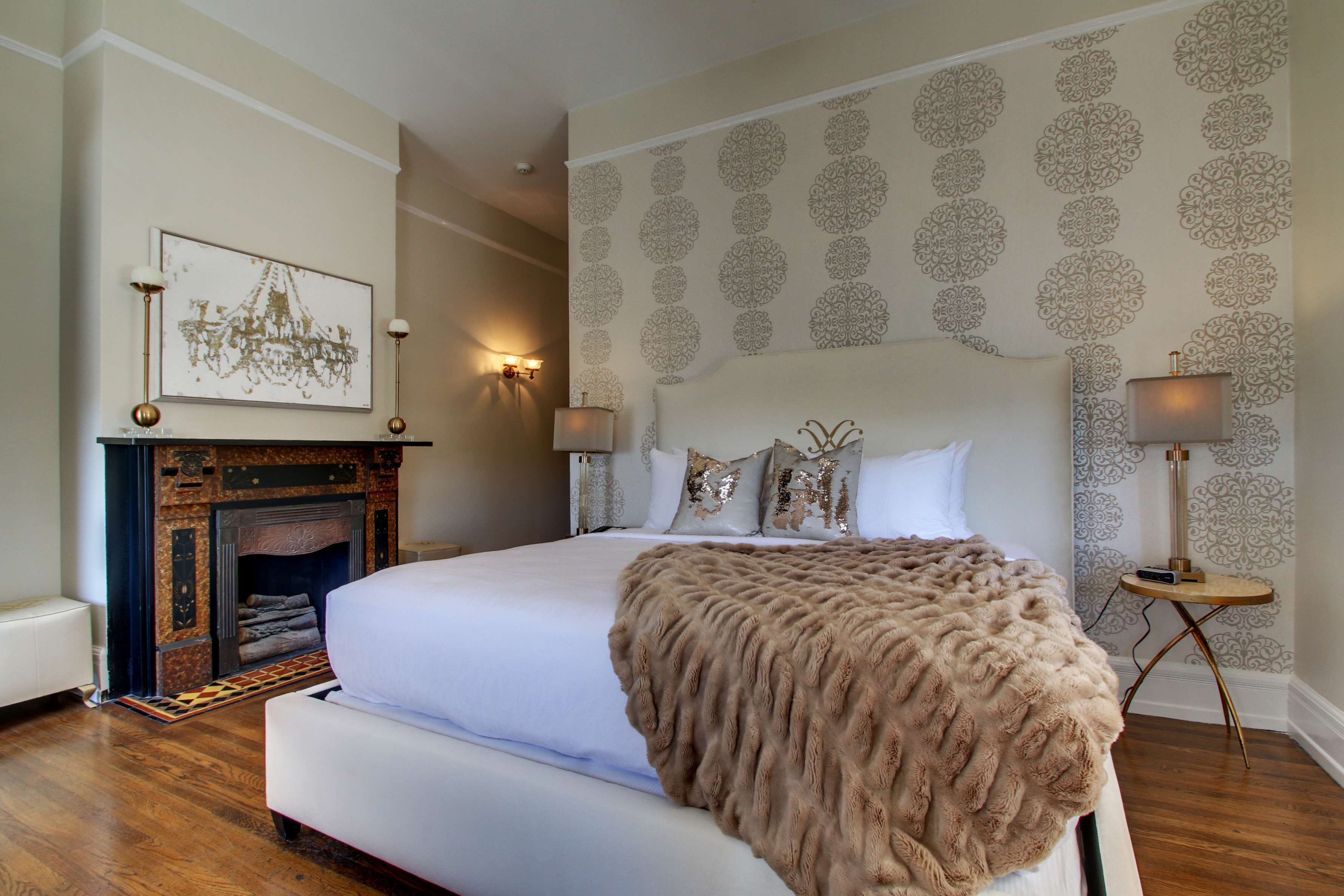 Quarto com uma cama grande, lareira e papel de parede estampado.