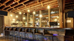 A bar area with wooden beams, hanging light fixtures, and bar stools. - Hotel Finial, BW Premier Collection (Anniston)