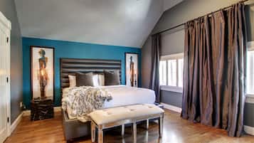 A bedroom with a large bed, a bench, and artwork on the walls.