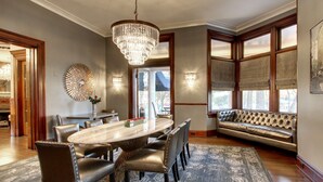 A dining area with a large oval table, leather chairs, a chandelier, and a patterned rug. - Hotel Finial, BW Premier Collection (Anniston)