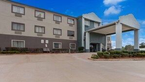 A multi-story hotel with a covered entrance, air conditioning units, and a parking lot. - Quality Inn & Suites Pearl - Jackson (Pearl)