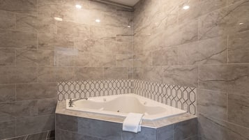 Un bagno moderno con una vasca freestanding, piastrelle in marmo e una fascia di piastrelle geometriche.