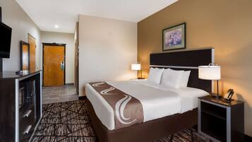 Una habitación de hotel con cama, lámparas de noche, televisión y escritorio.