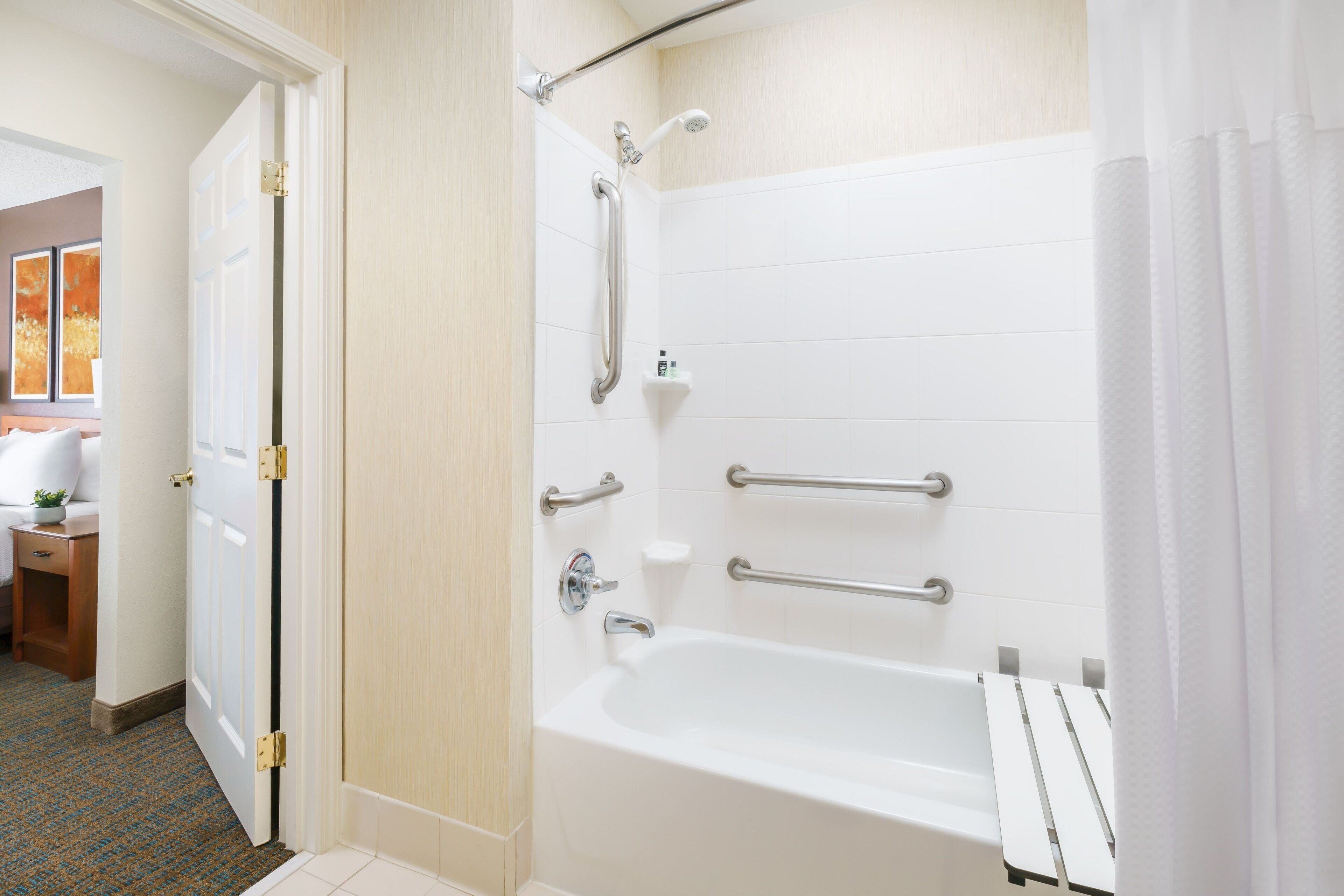 A modern bathroom with a walk-in shower, grab bars, and a white bathtub.