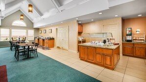 Una cocina amplia con comedor, armarios de madera y una estación para café.