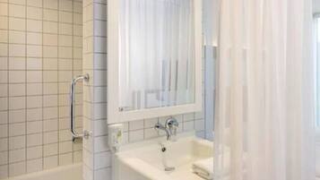 Un baño con pared de azulejos blancos, una bañera, un lavabo con espejo y una cortina de ducha.