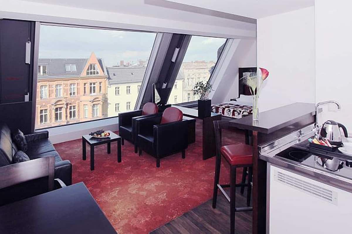 A modern apartment with a dining area, kitchen, and seating space with a city view.
