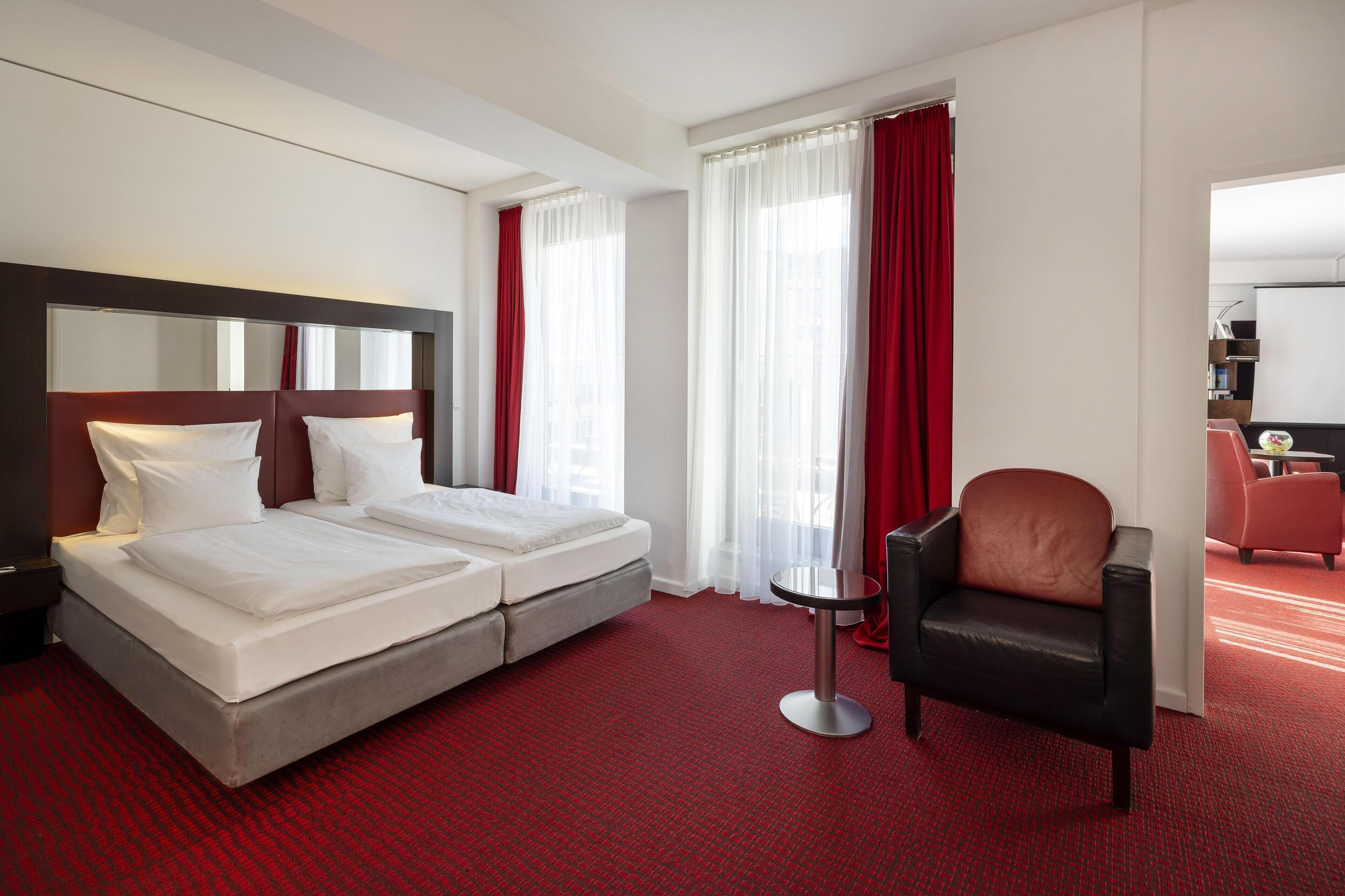 Una habitación de hotel con una cama doble, un escritorio, una silla y un espejo grande.