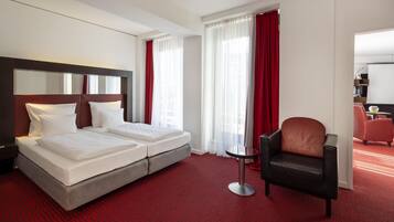 A hotel room with a double bed, a desk, a chair, and a large mirror.