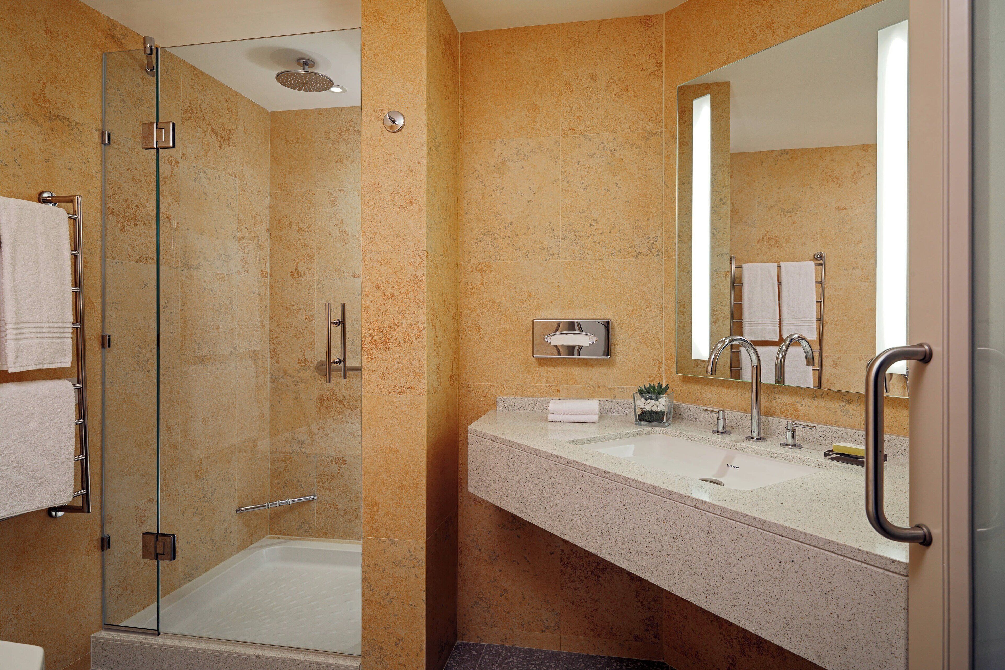 A bathroom with a glass-enclosed shower, a sink with a mirror, and a towel rack.
