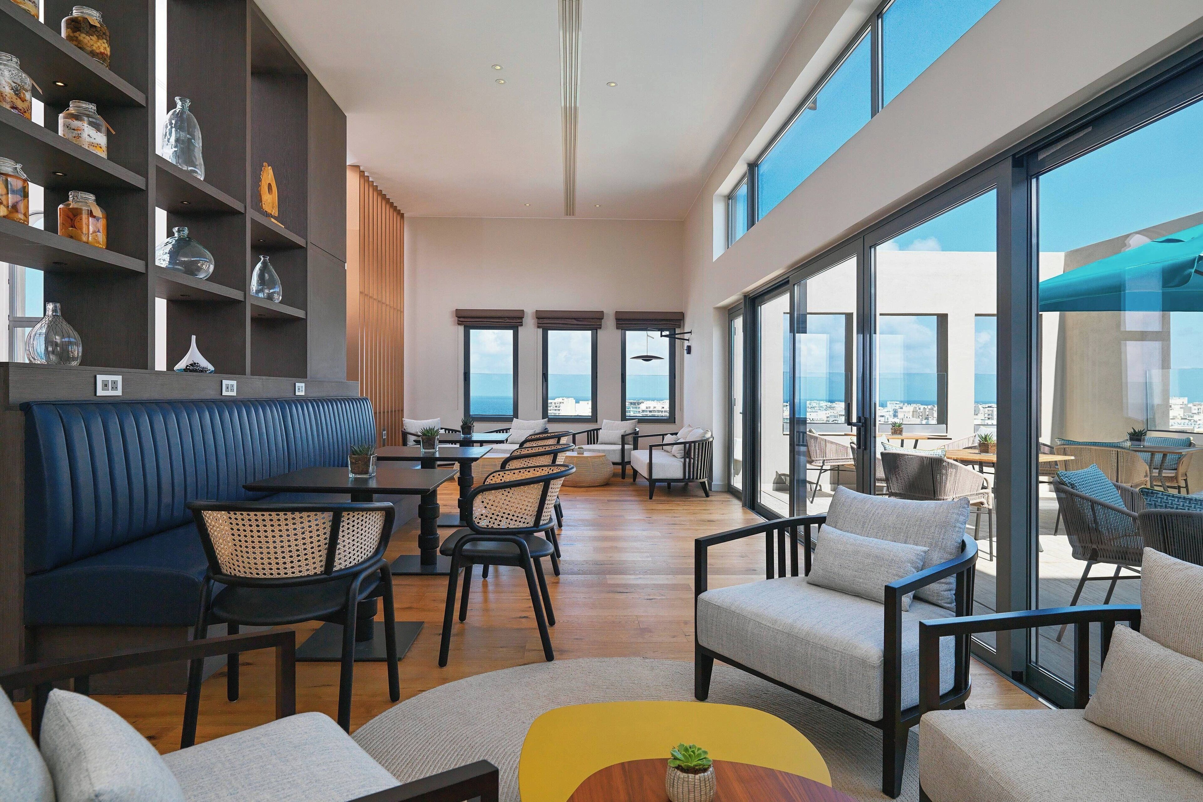A modern lounge area with seating, a coffee table, and a bookshelf with decorative items.
