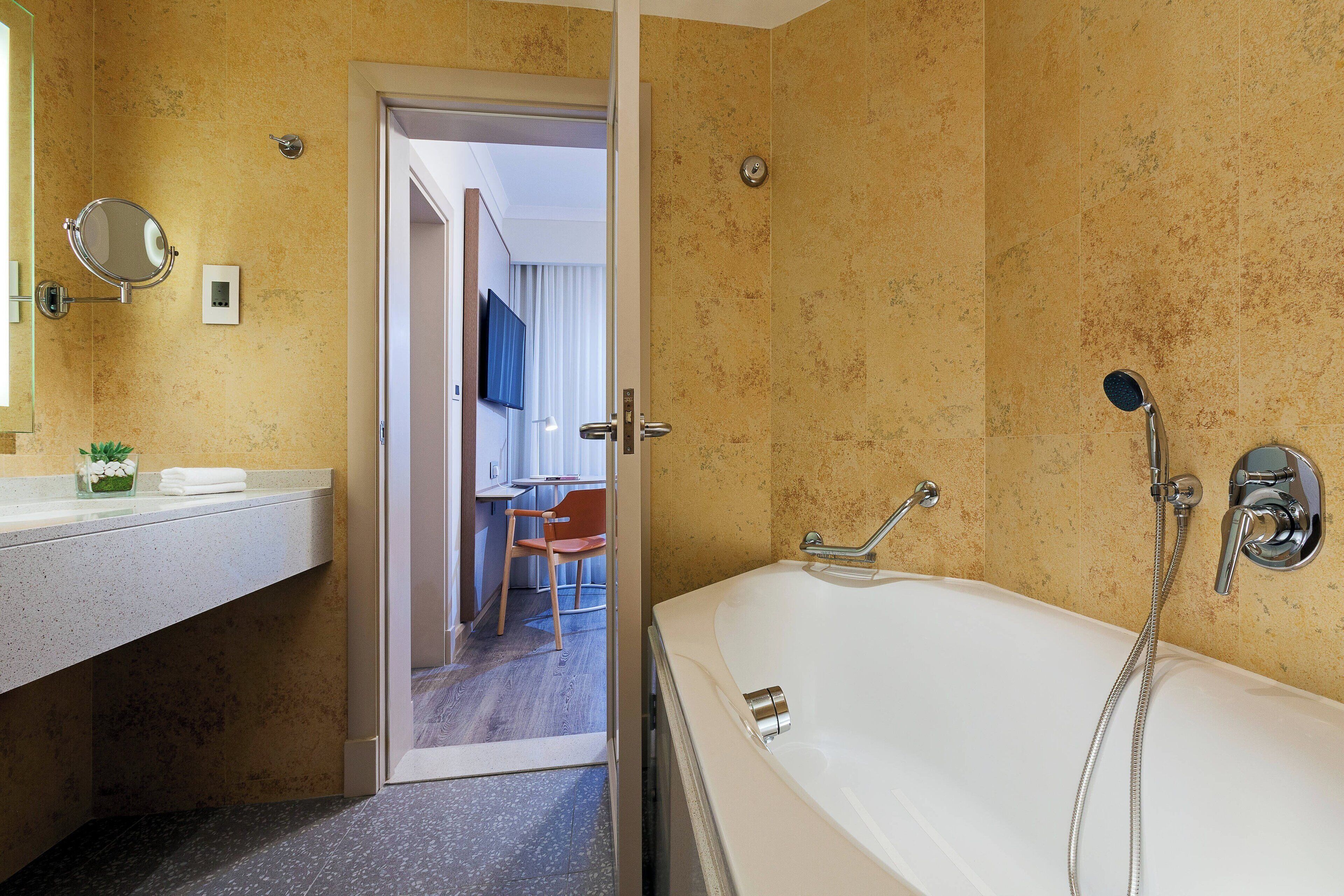 A modern bathroom with a bathtub, shower, and a vanity with a mirror.