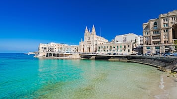 Eine Küstenstadt mit einer markanten Kirche, klarem türkisblauem Wasser und einer Uferpromenade.