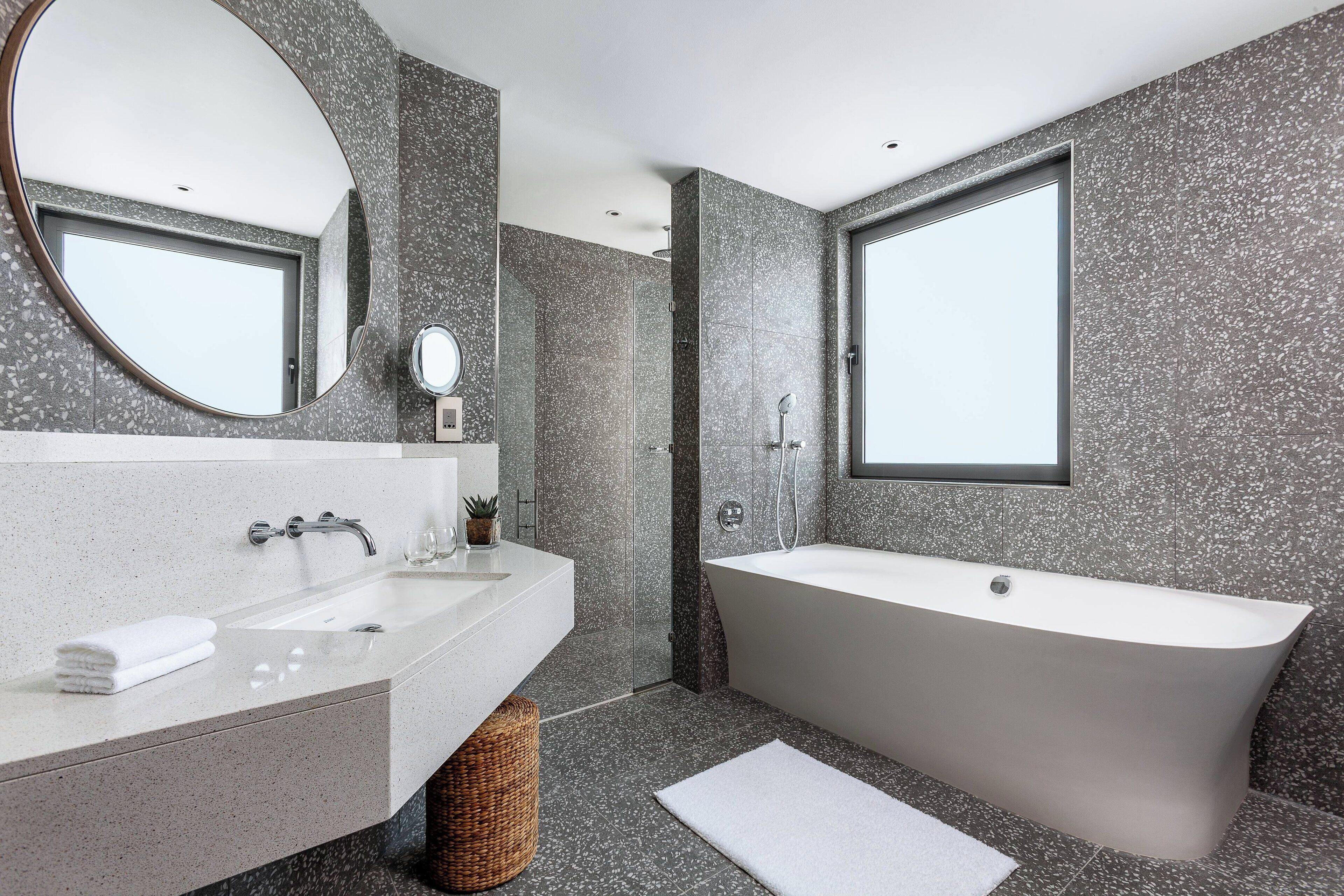 A modern bathroom with a freestanding bathtub, a large mirror, and a sink with a countertop.