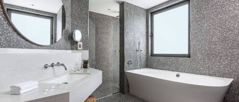 A modern bathroom with a freestanding bathtub, a large mirror, and a sink with a countertop.