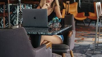 A modern hotel lobby with a dining area, featuring a laptop on a table, a globe, and contemporary furniture.