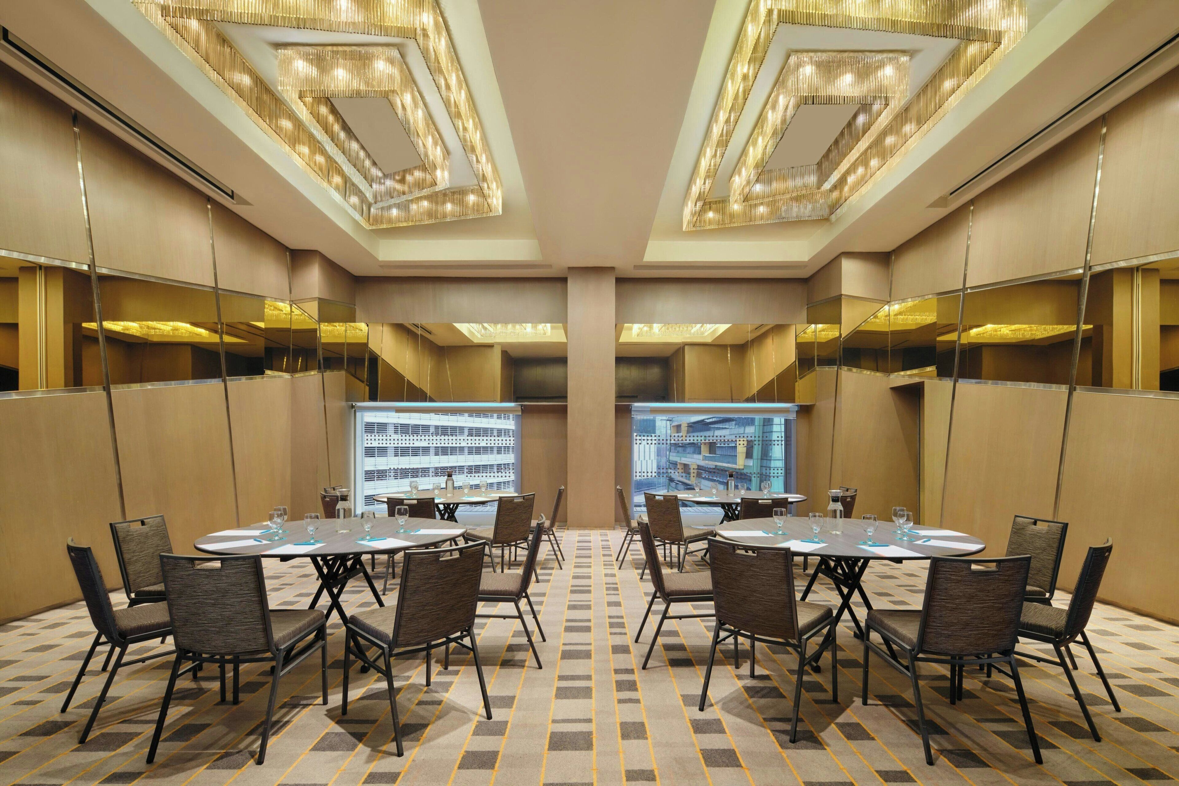 A conference room with a large screen, multiple tables, and chairs.