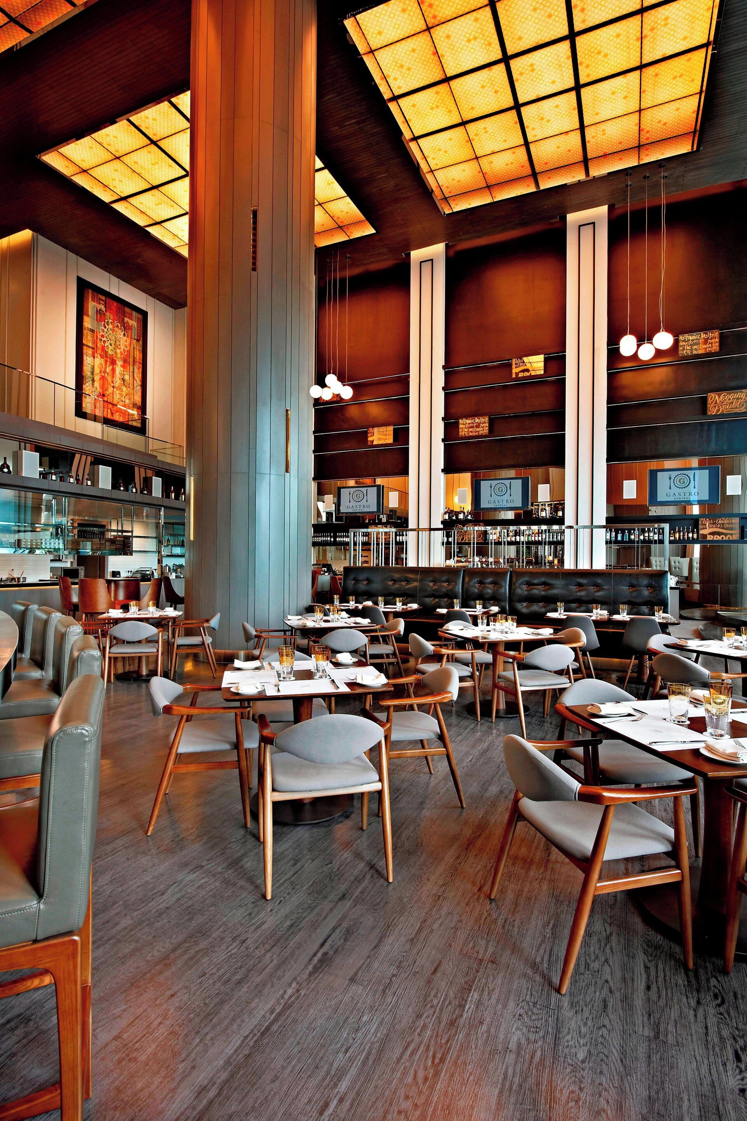 A spacious restaurant with high ceilings, wooden flooring, and a variety of seating options including tables and booths.