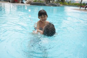 A child playing in a swimming pool with clear water and a few rocks visible in the background. - Le Méridien Kuala Lumpur (Kuala Lumpur)